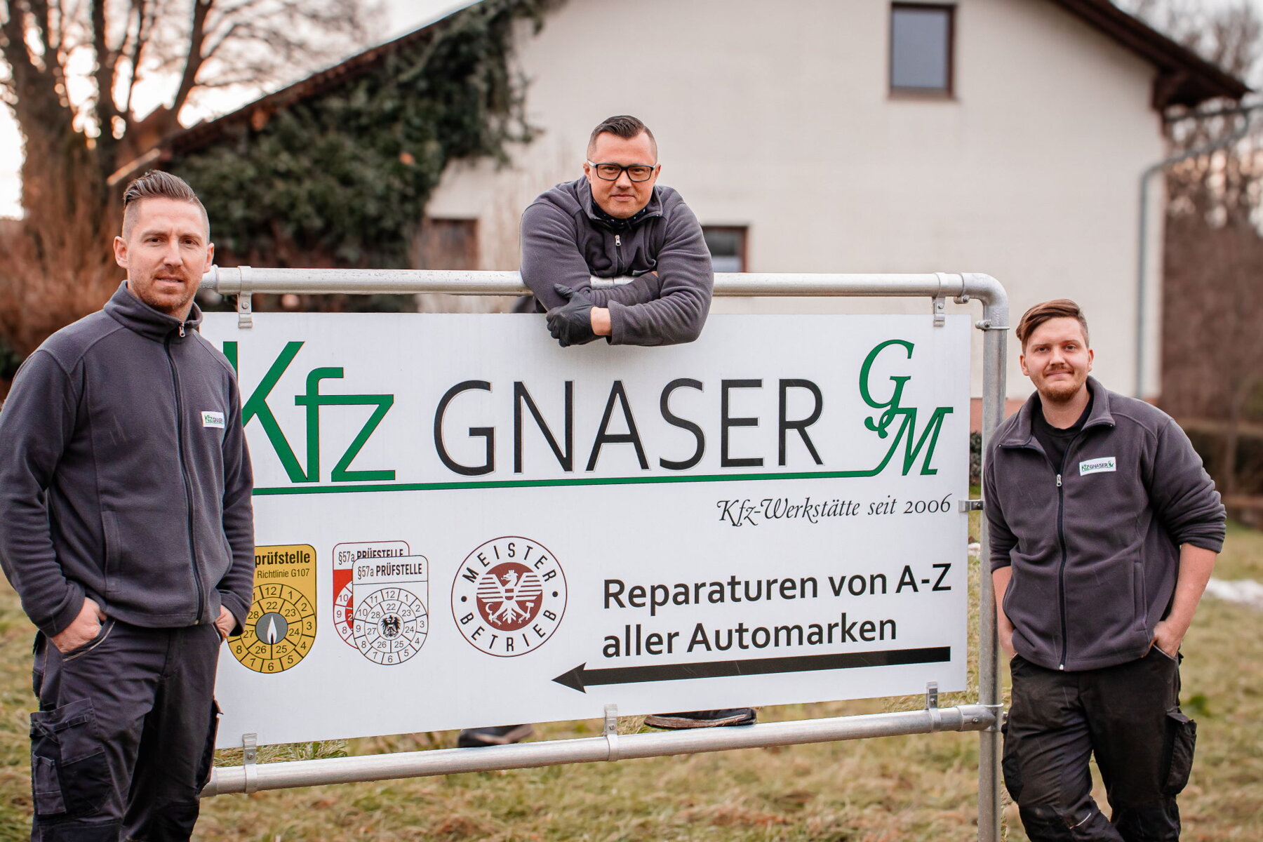 Team von KFZ Gnaser Meisterbetrieb vor Schild